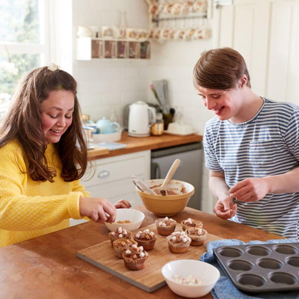 Young woman and man baking cupcakes in kitchen